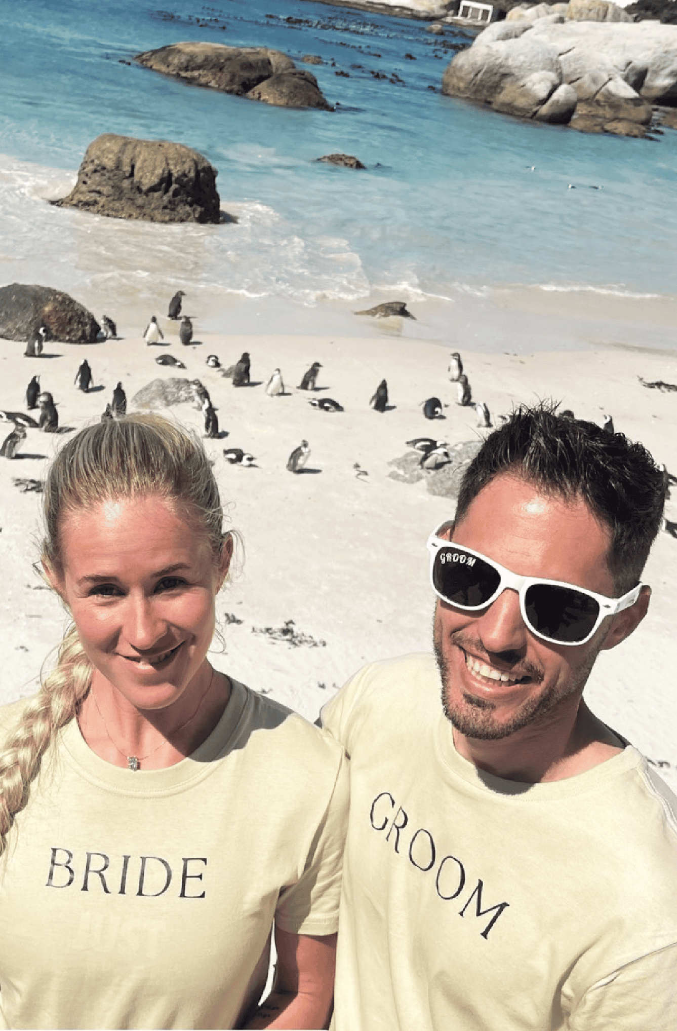 Models wear Bride and Groom T-shirts in a khaki colour while on the beach with penguins