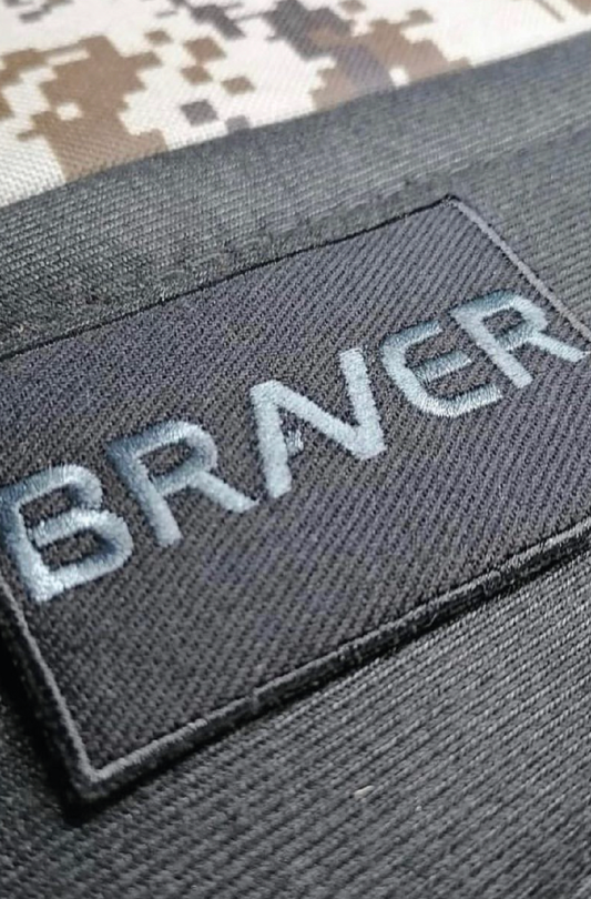 Velcro patch embroidered in black with the word braver