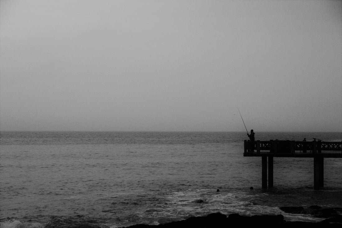 Black and white photo of a fisherman at Herold's Bay, South Africa, taken in 2021 by guest writer Ruan Van Rensburg