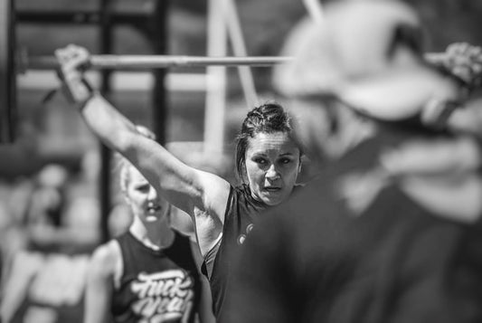 Woman lifting barbell overhead wearing braver
