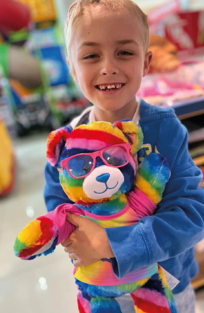 Hunter Emms holding a rainbow teddy bear