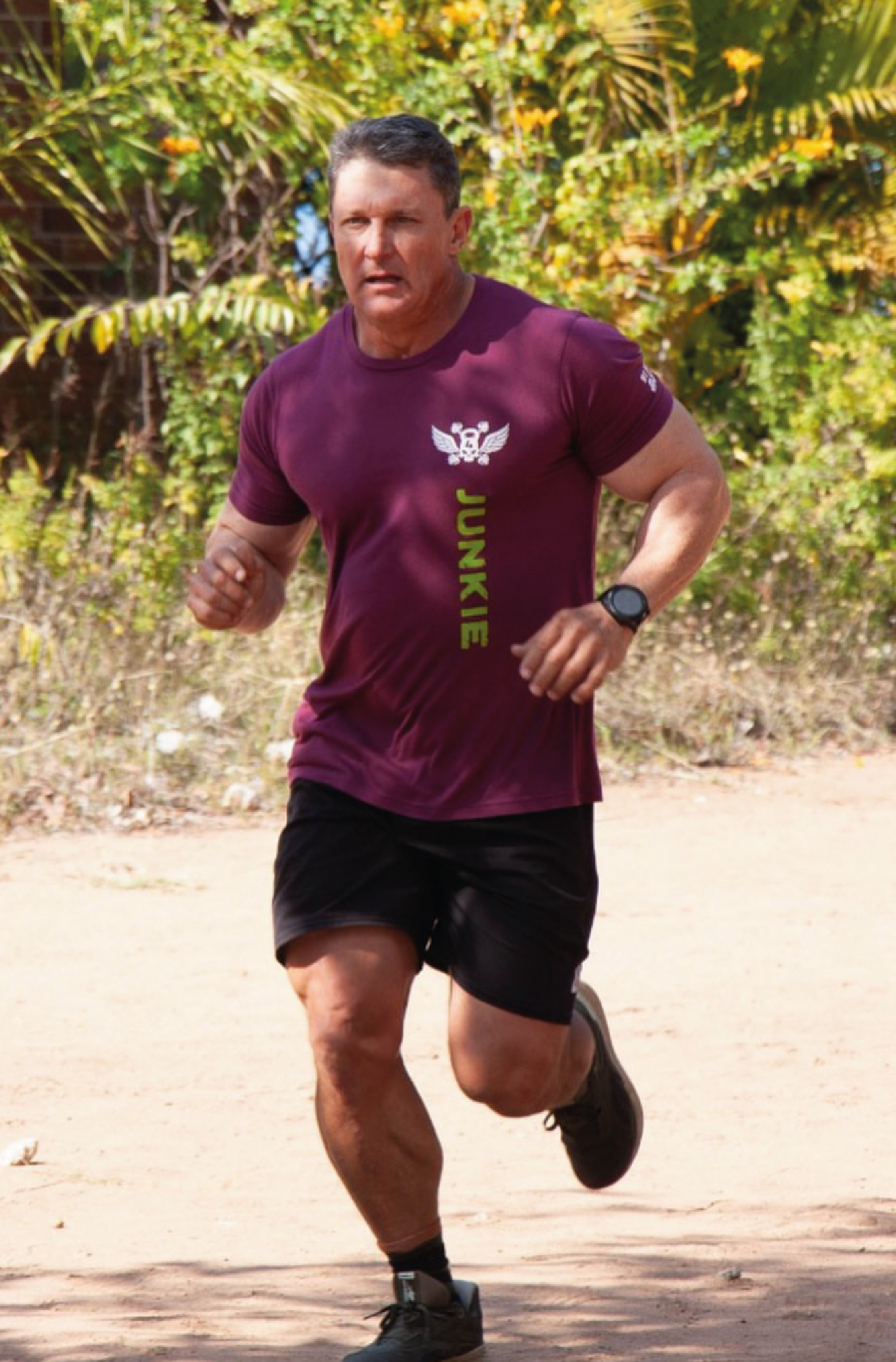 Man running wearing a maroon unisex t with custom vinyl printing on in white and neon green