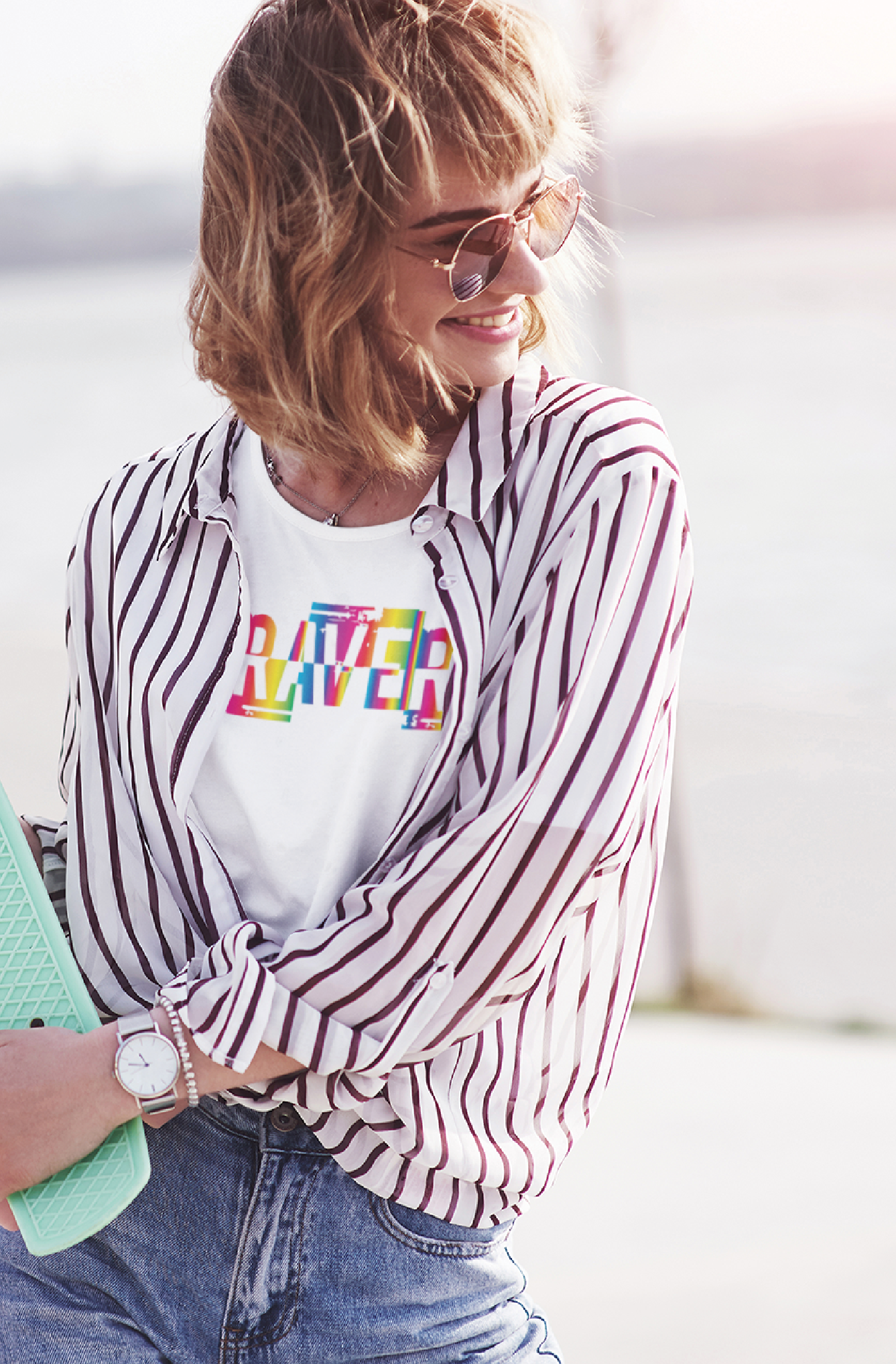 Women with skate board wearing a white braver print in rainbow styled with smart casual shirt and other accessories