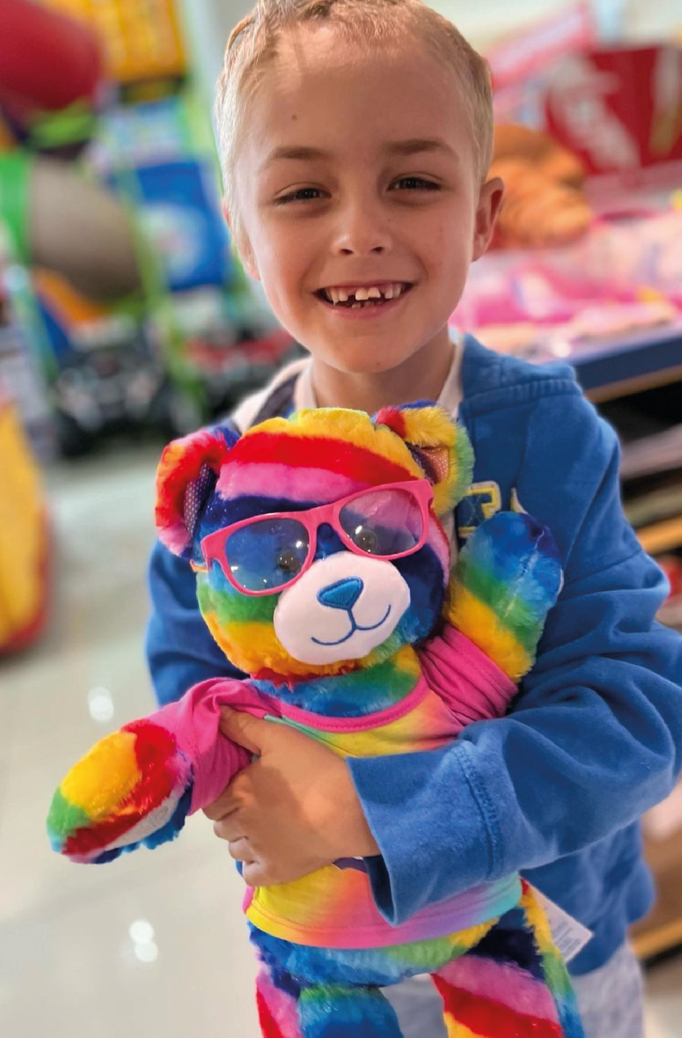 Hunter Emms pictured with a rainbow teddy bear, this is the boy you're supporting when you purchase a Dear Hunter print in our shop