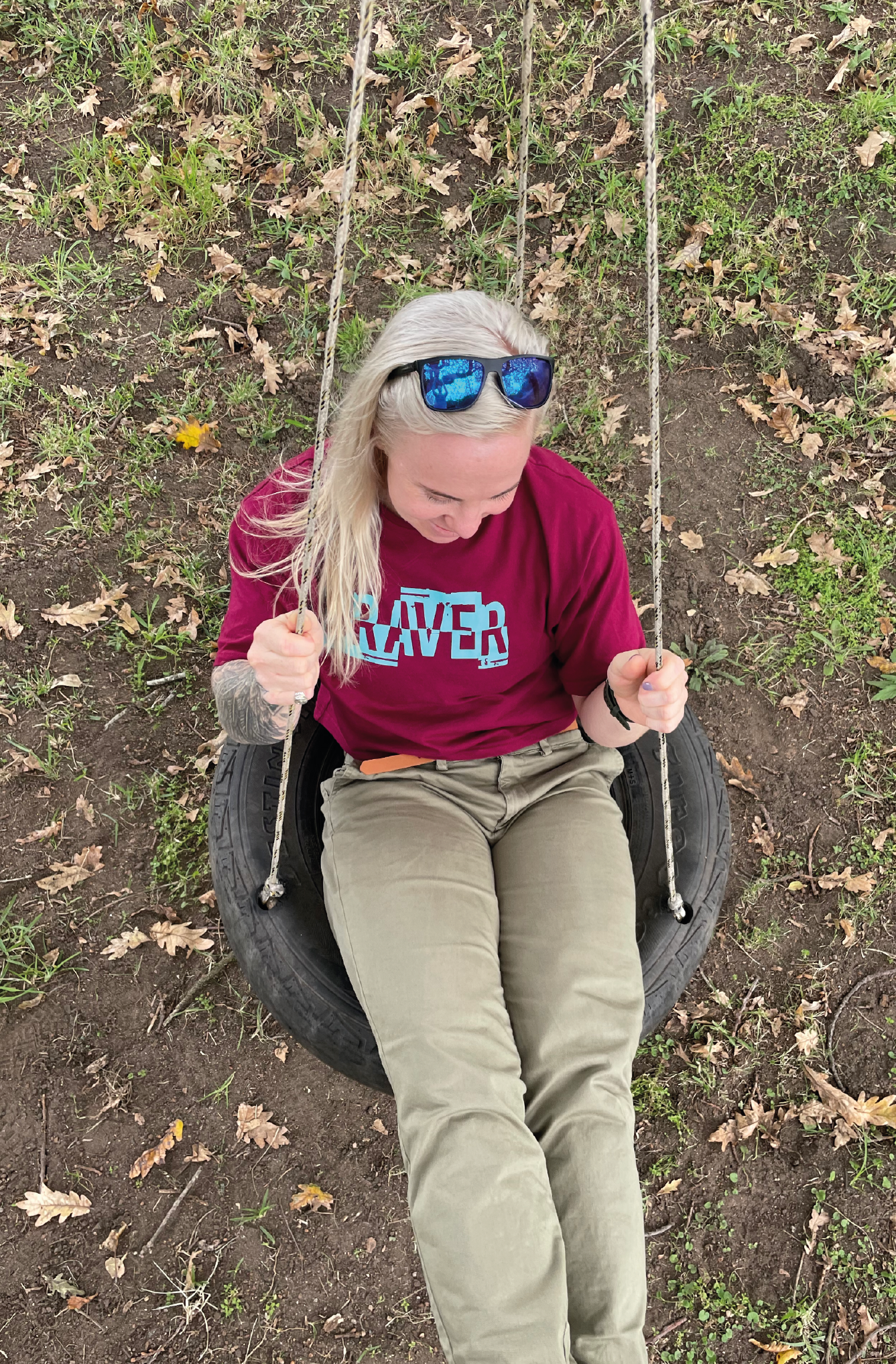 Women on a tyre swing wearing cargo pants with a maroon crop top and sunglasses.