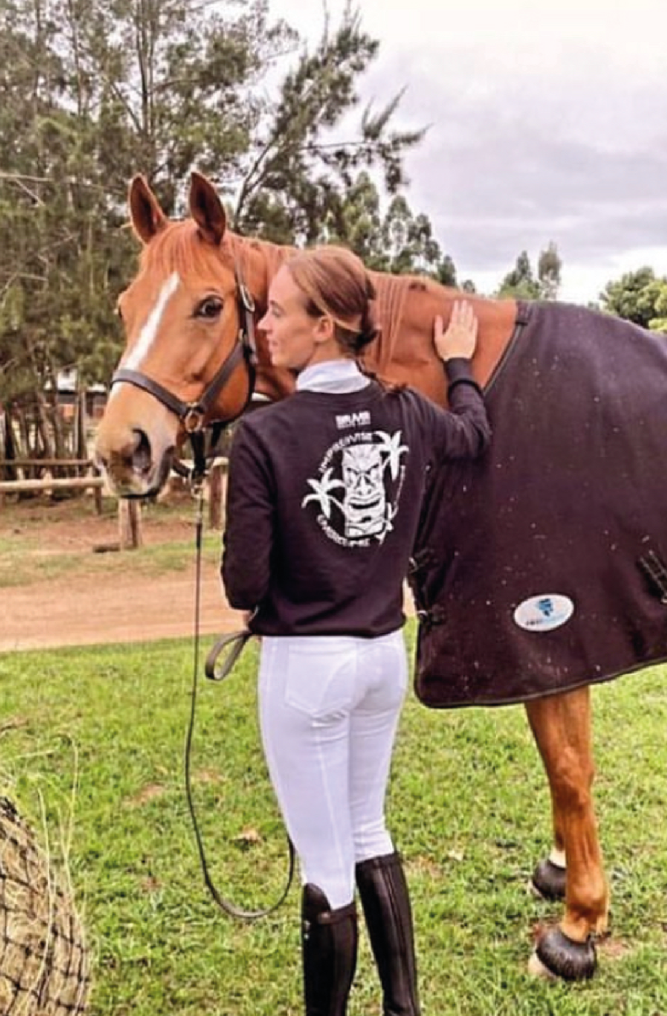 Woman wearing a braver black sweater with custom print standing with a horse