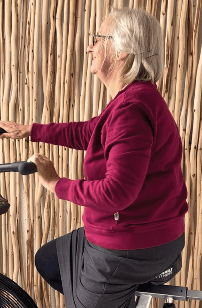 Woman on assault bike wearing a braver maroon sweater