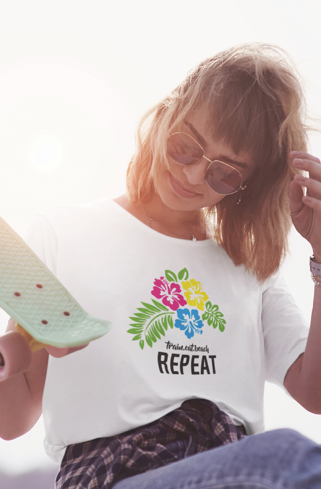 Women with skate board wearing a white tshirt with neon hibiscus flowers and typographic elements on